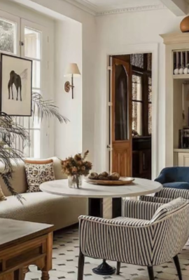 Bright sitting room with a round table, striped armchair, dried flowers and a patterned tile floor